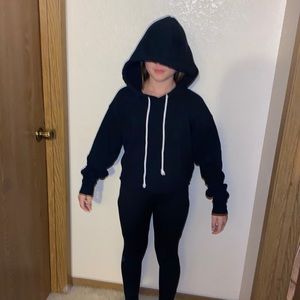 Black women’s crop top sweatshirt with hood and white drawstrings.